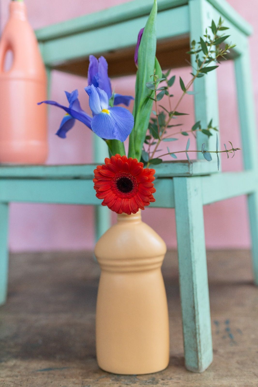 un vaso pieno di fiori è seduto su uno sgabello blu