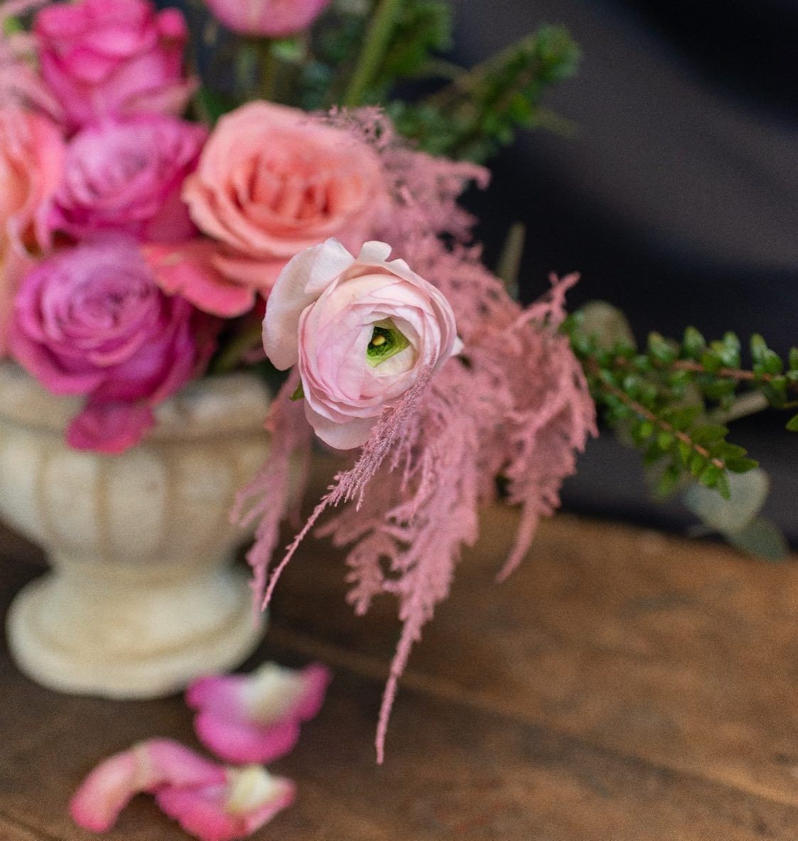 un vaso pieno di fiori rosa è seduto su un tavolo di legno .