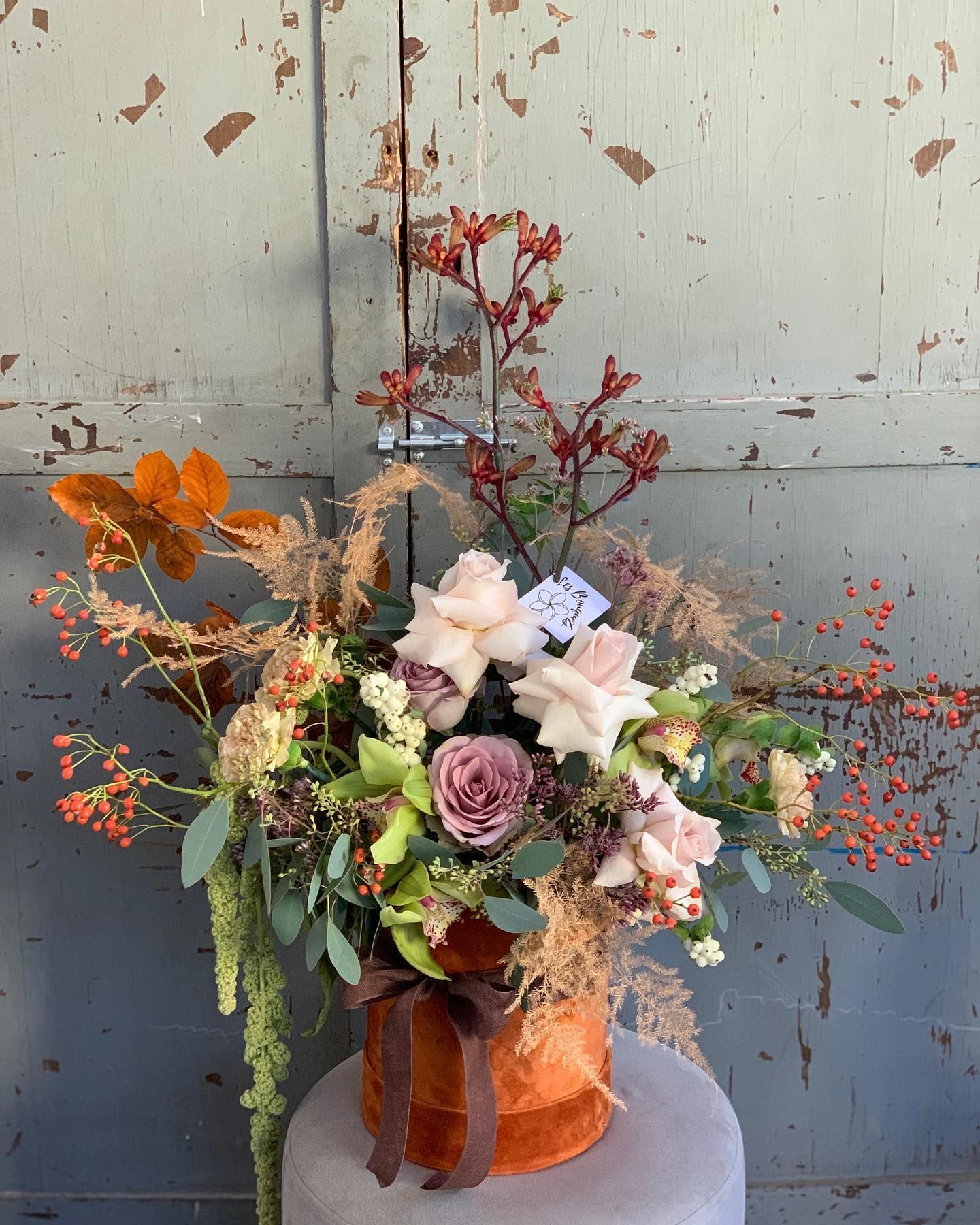 un vaso pieno di fiori è seduto su un tavolo davanti a una porta .