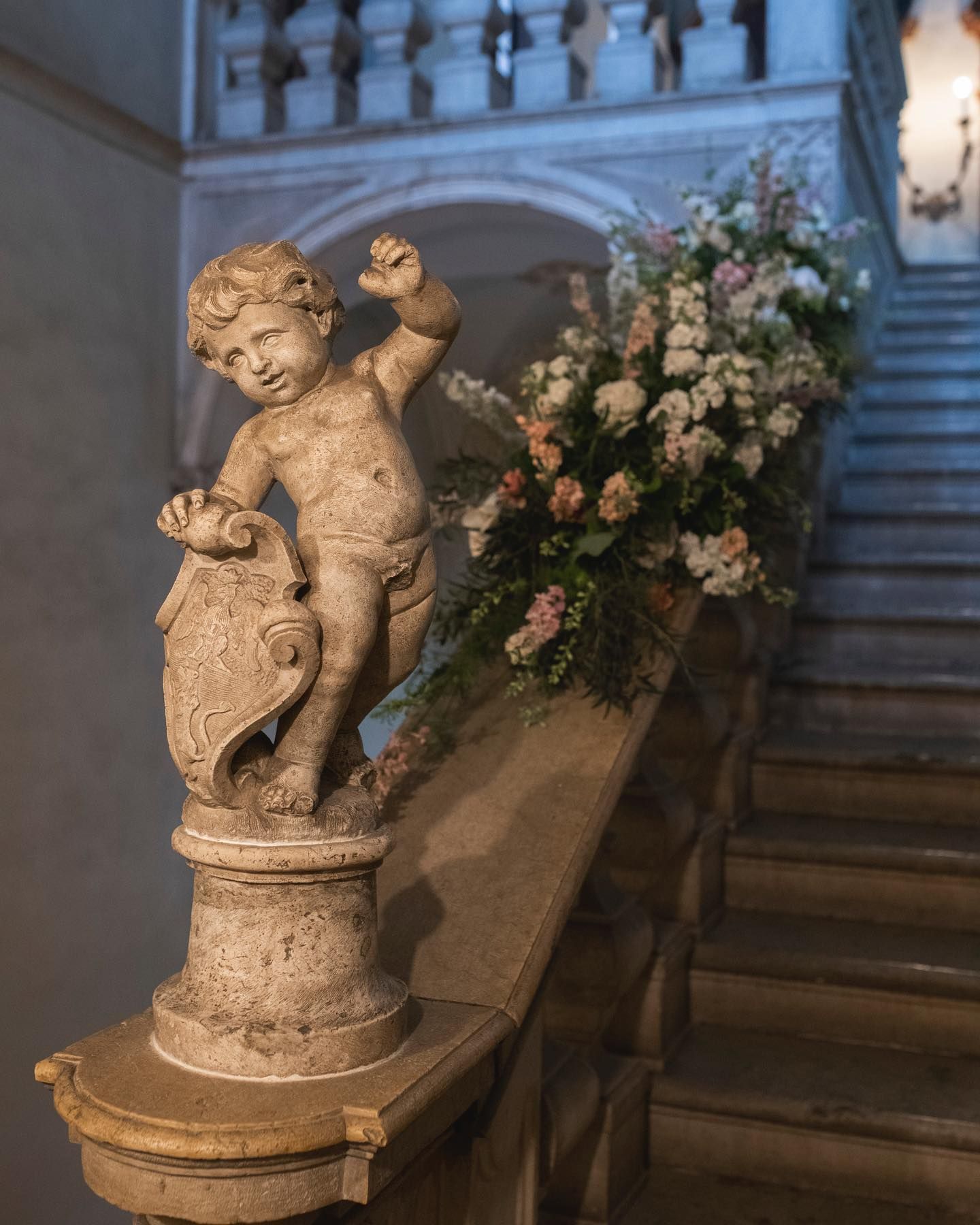 una statua di un bambino in piedi su una scala accanto a un vaso di fiori .
