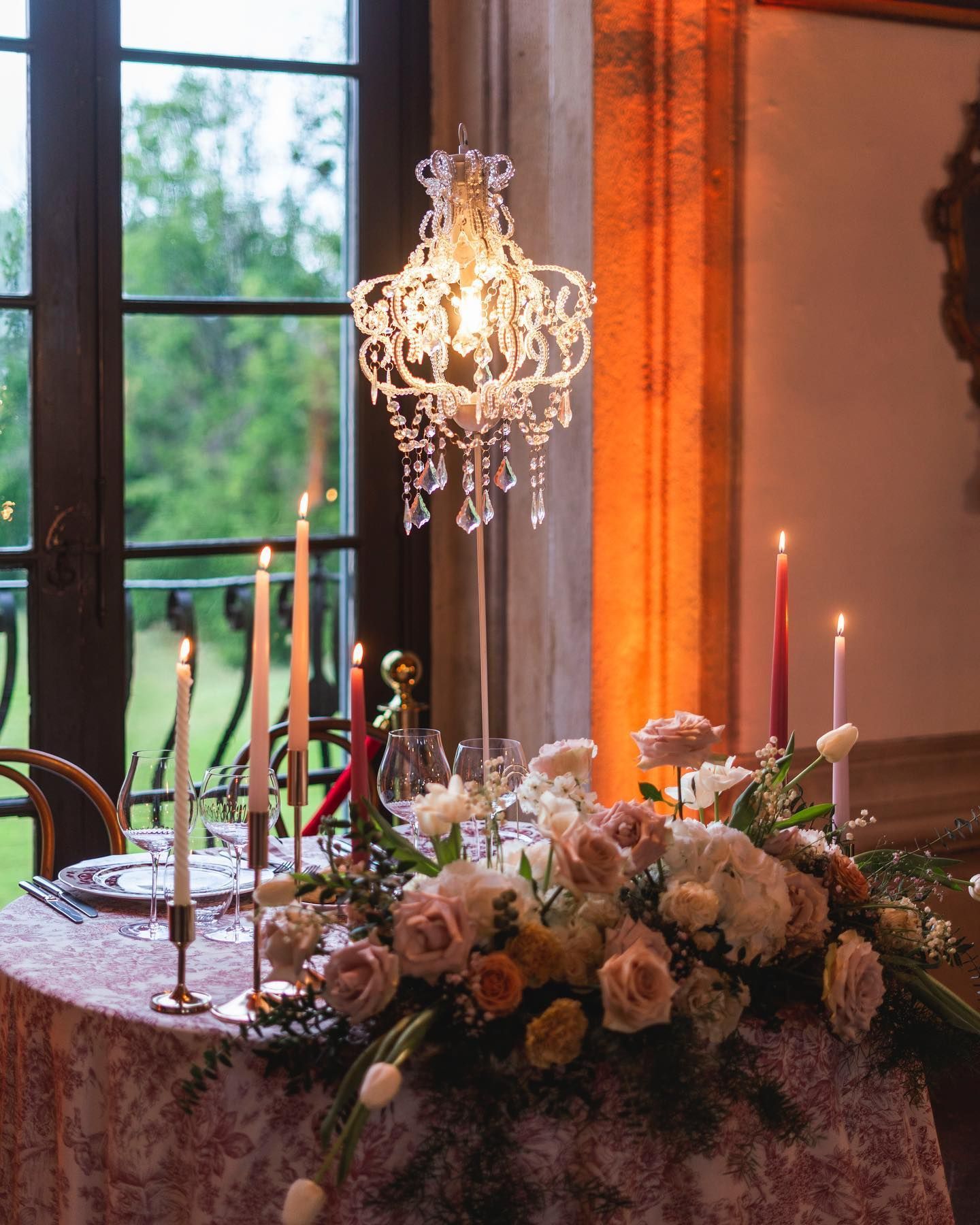 un tavolo decorato con fiori , candele e un lampadario .