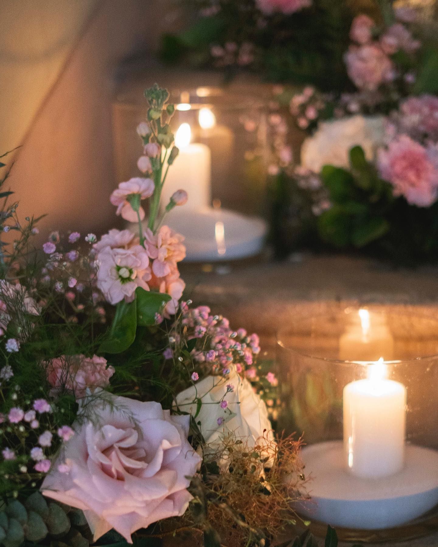 ci sono molti fiori rosa e candele su un tavolo .