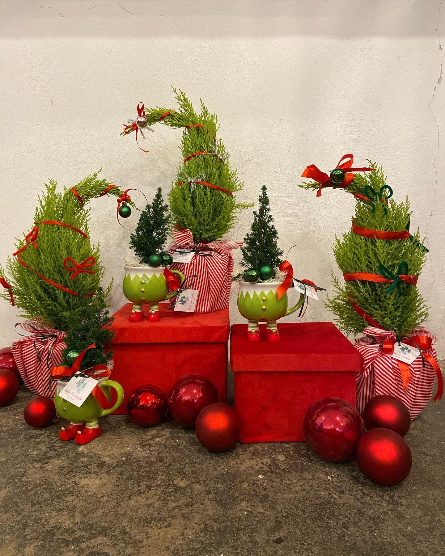 un gruppo di alberi di natale in vaso su scatole rosse circondate da palline rosse .