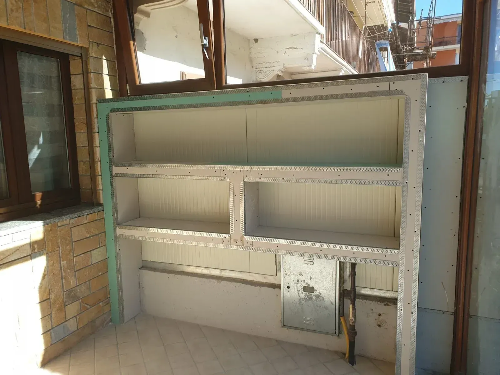 Scaffalatura integrata in costruzione con isolamento e ripiani aperti, su un balcone.