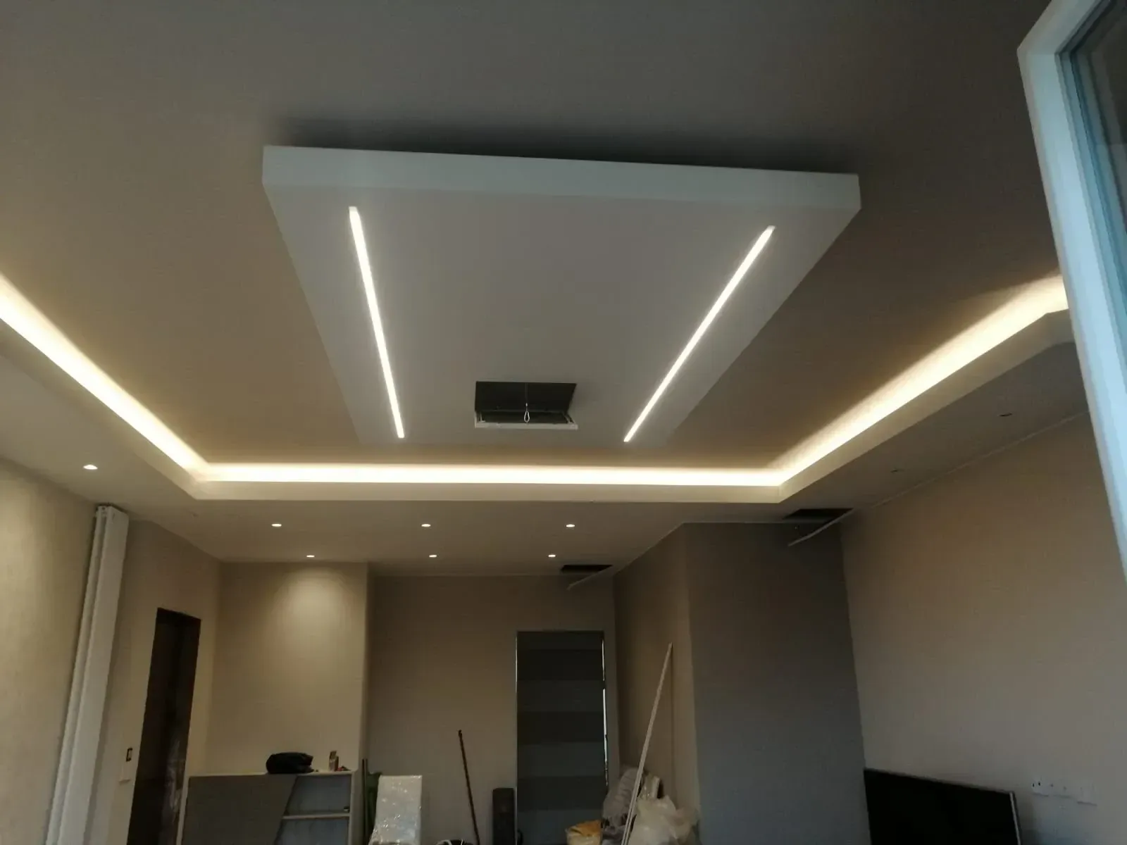 Soffitto bianco con illuminazione da incasso, tra cui un design quadrato e luci lineari.