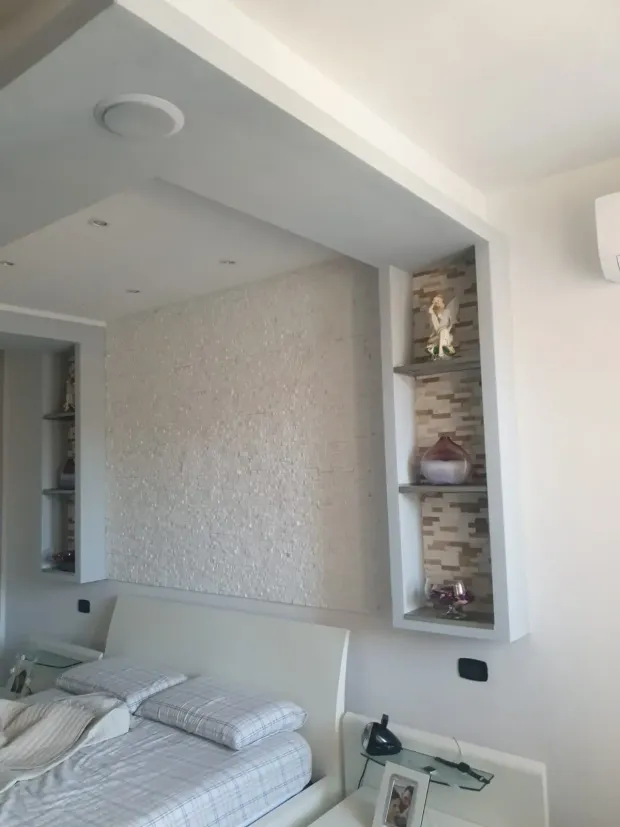 Sistema di grondaie nere su una casa bianca con cielo azzurro sullo sfondo.