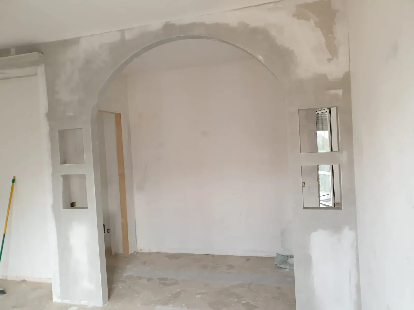 Spazio interno con arco in gesso e nicchie in una parete. Lavori in corso.