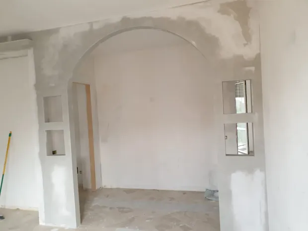 Un operaio edile installa tegole di ardesia grigio scuro su un tetto, con travi di legno visibili.