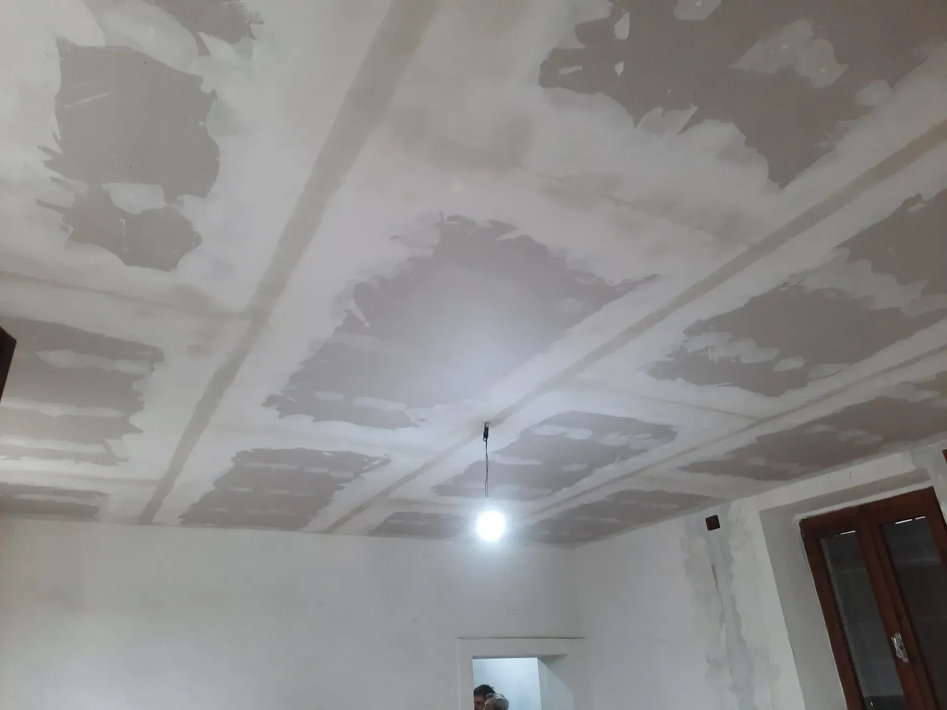 Soffitto con toppe in cartongesso, lampadario, stanza in costruzione.