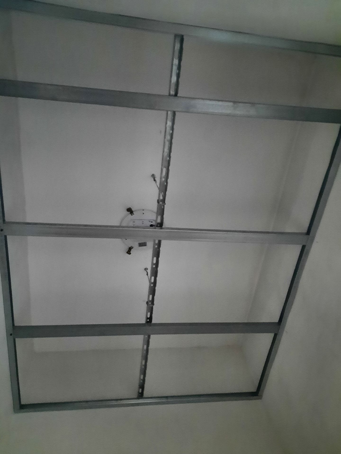 Struttura del soffitto con struttura in metallo e fili, contro un soffitto bianco.