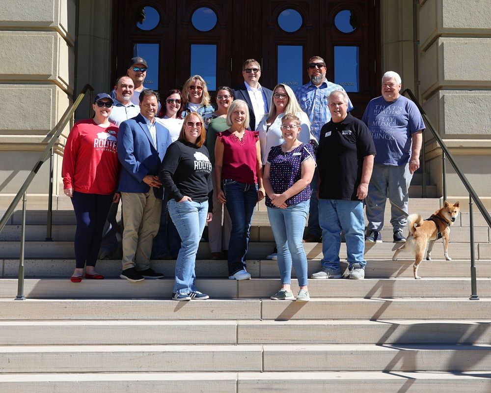 Group of people posing on steps in front of a building with a dog.