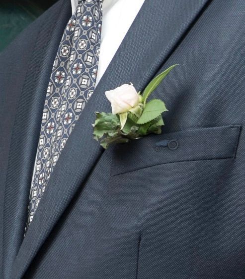 Mann i marineblå dress med boutonniere og mønstret slips.
