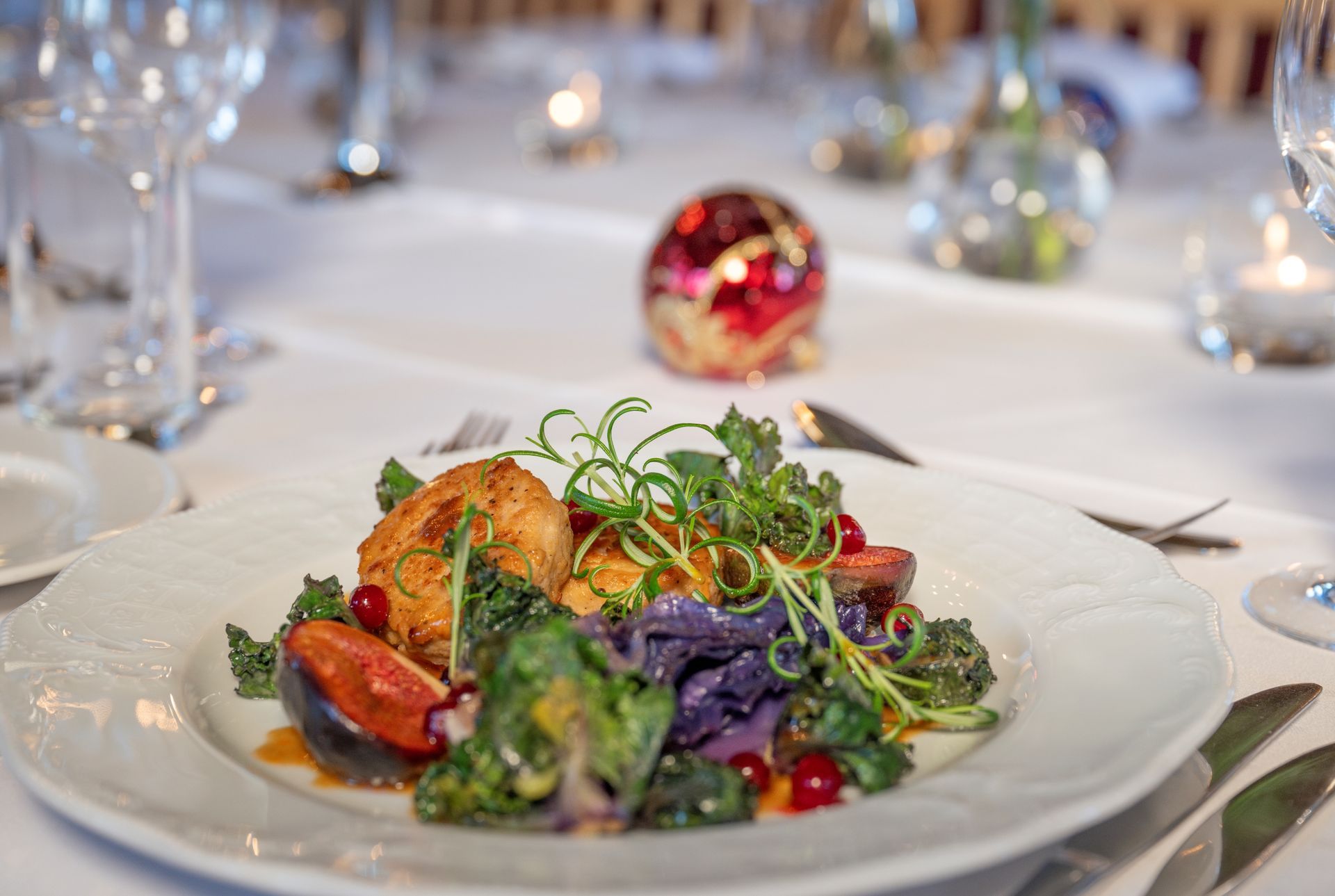 Tallerken med gourmetmat: stekt mat, fargerike grønnsaker og bær på en hvit duk, elegant setting.