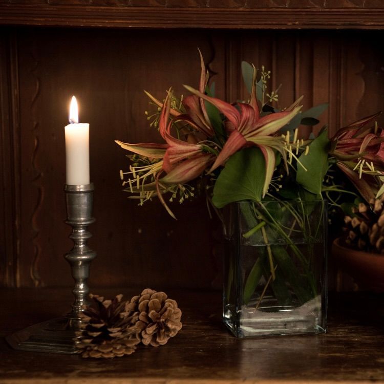 Glassvase med grøntområder på en trehylle, mørkeblå bakgrunn.