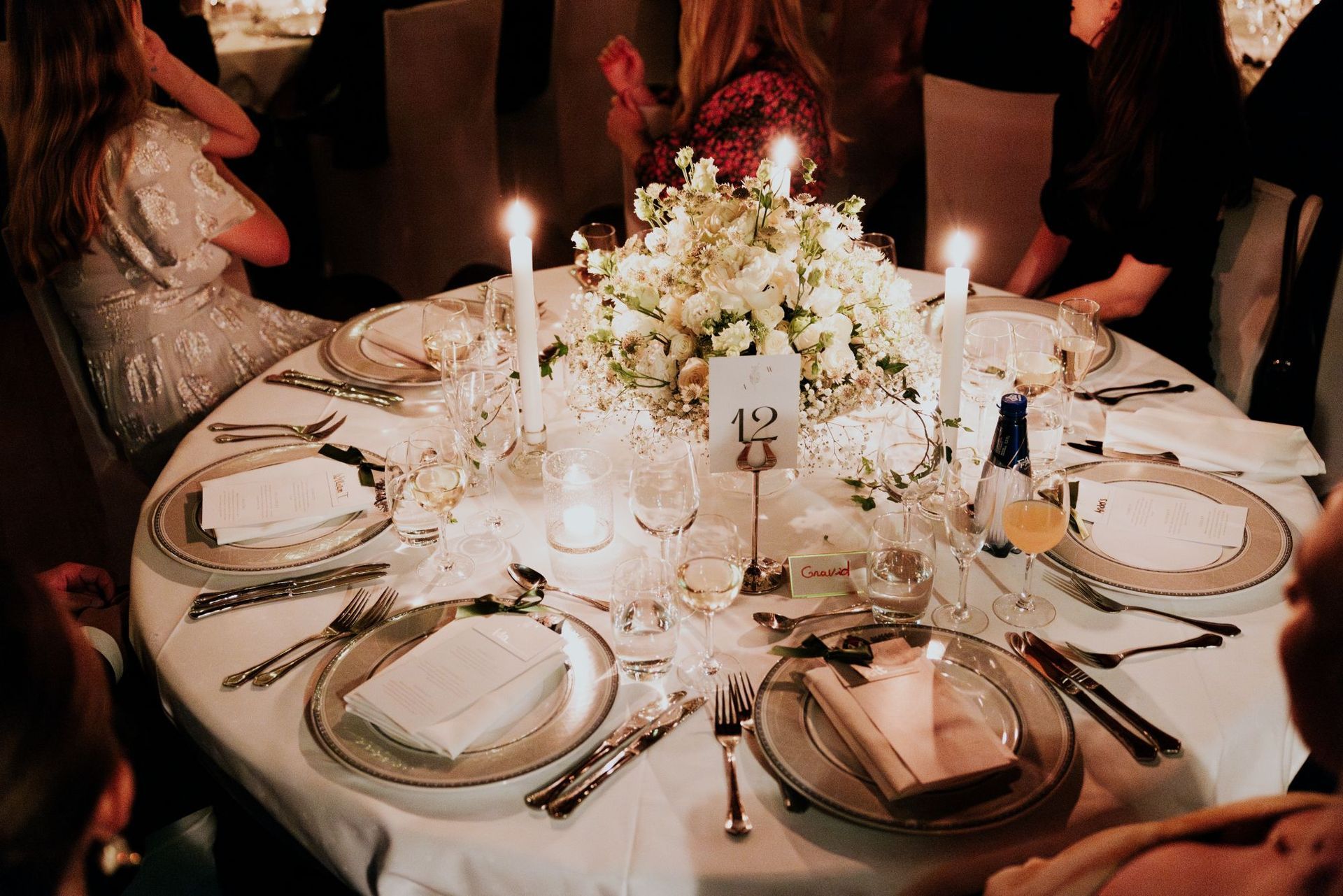 Formelt spisebord med hvit duk, tallerkener, sølvtøy og en dekorert serviett.