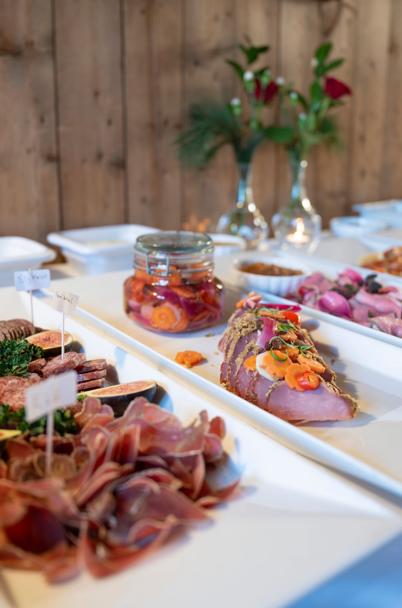 Et bord med charcuterie: spekemat, fikenskiver, syltede grønnsaker og en sennepsdeig.