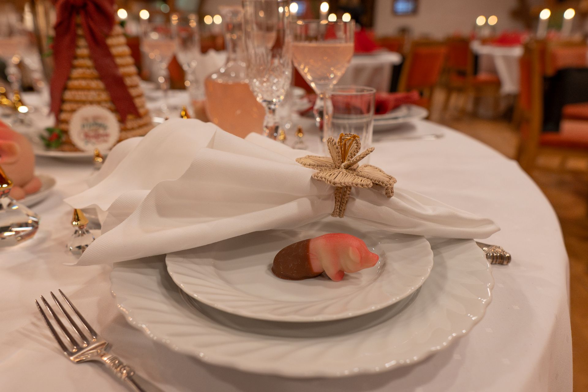 Formelt spisebord med hvit duk, tallerkener, sølvtøy og en dekorert serviett.