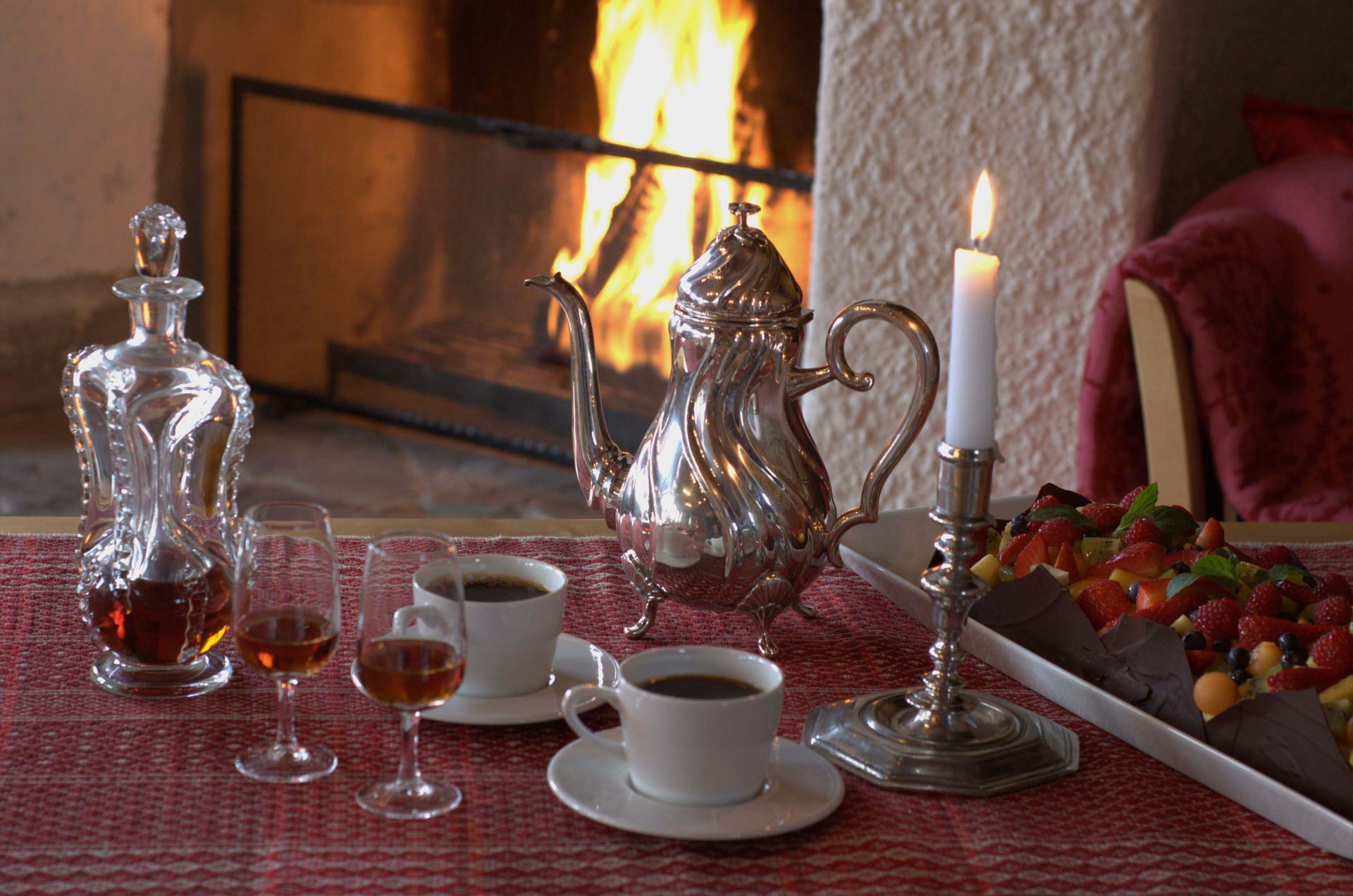 Peis med kaffe, bakverk, karaffel, tent lys på rød duk.