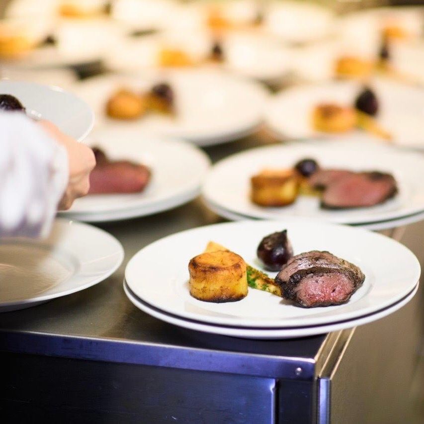 Tallerkener med mat tilberedes på et kjøkken: biff og potet. 