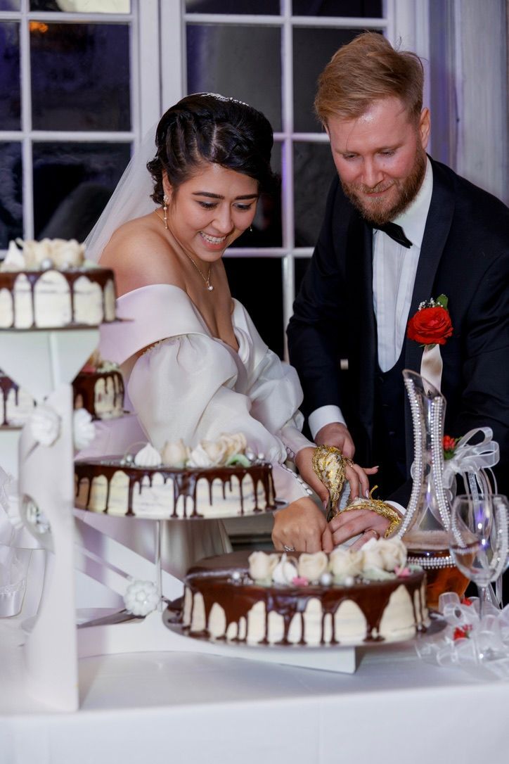 Brudeparet skjærer en sjokoladedekket kake i etasjer i en bryllupsfest.