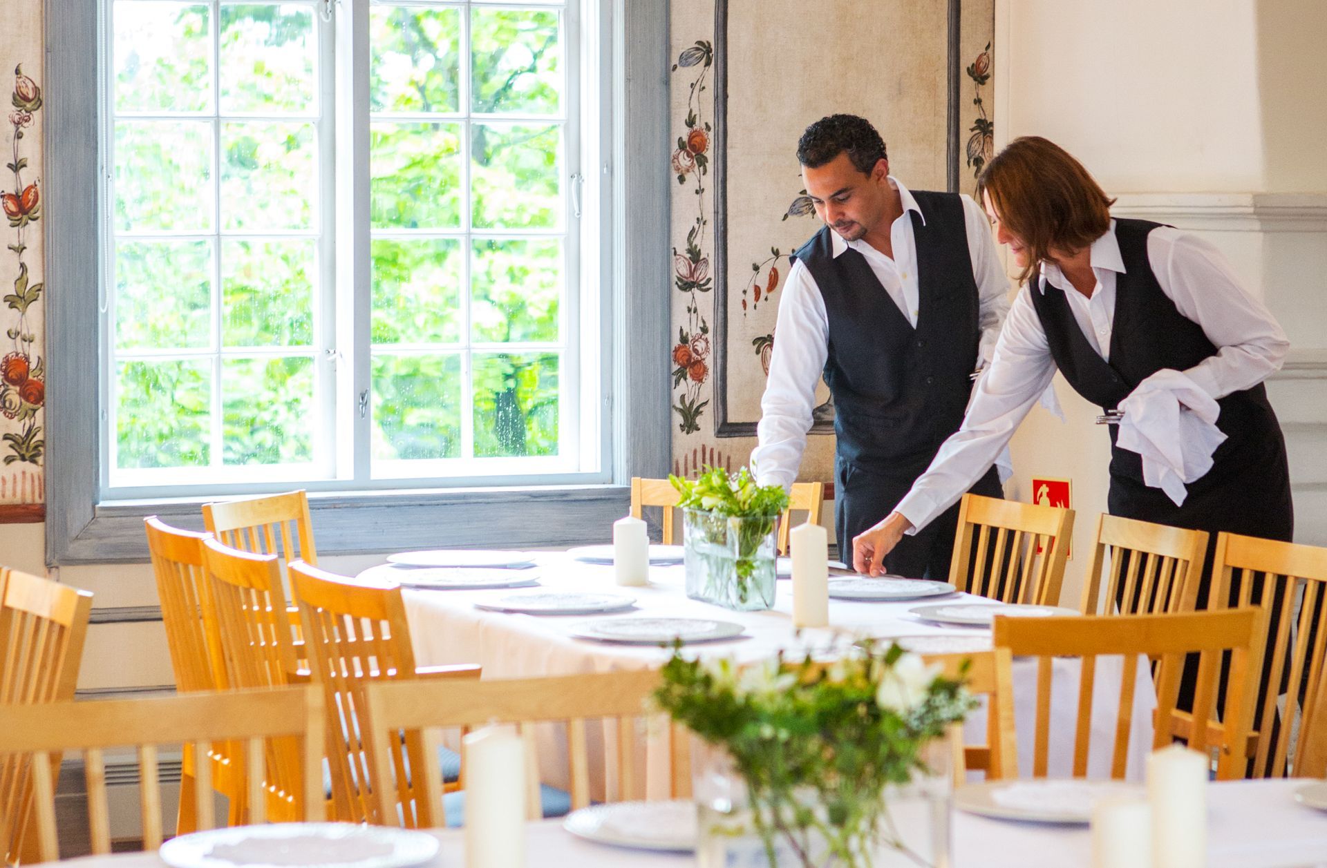 To servitører som dekker bordet i Festsalen på Gjestestuene