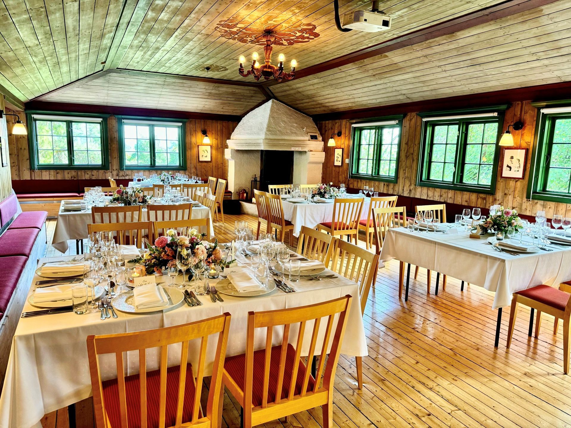 En stavkirke av tre med et lagdelt tak av shingel, plassert i en frodig grønn skogslysning.