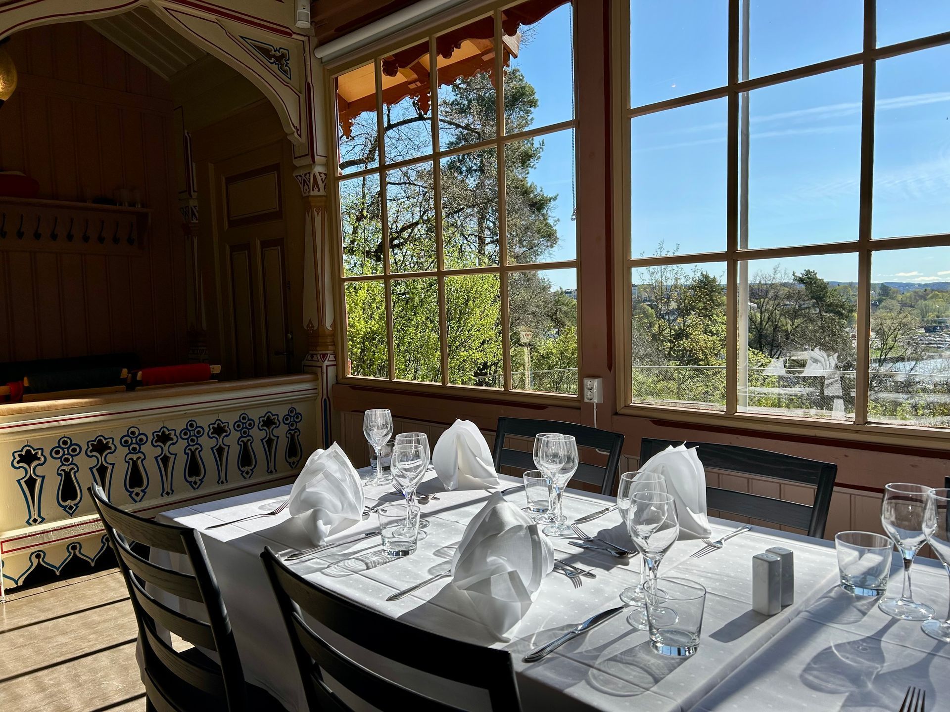 To unge mennesker i dress inne i en bygning, den ene retter på jakken sin, bord med en hvit duk synlig.