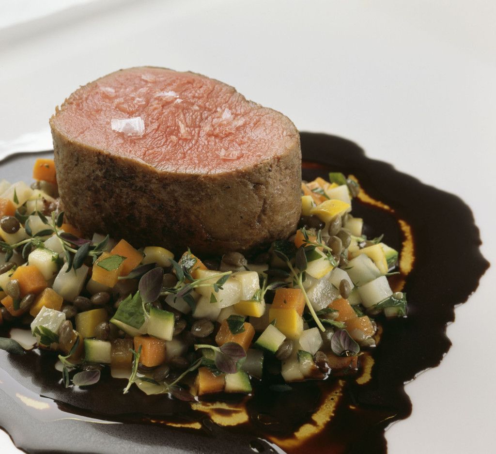 Kjøttmedaljong på en grønnsaksblanding, dynket med mørk saus.