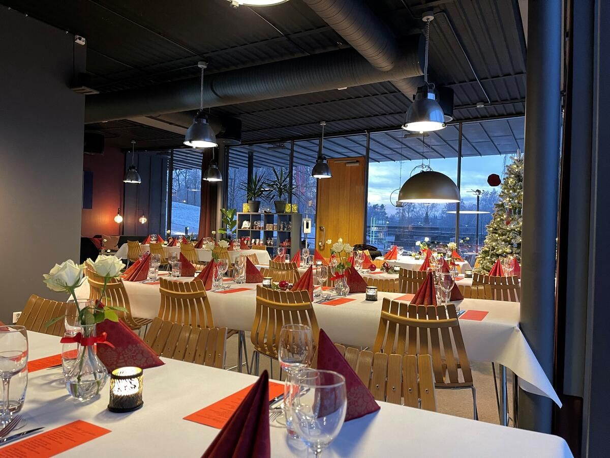 Langt bord dekket til en formell middag i et rustikt rom med peis og vinduer.