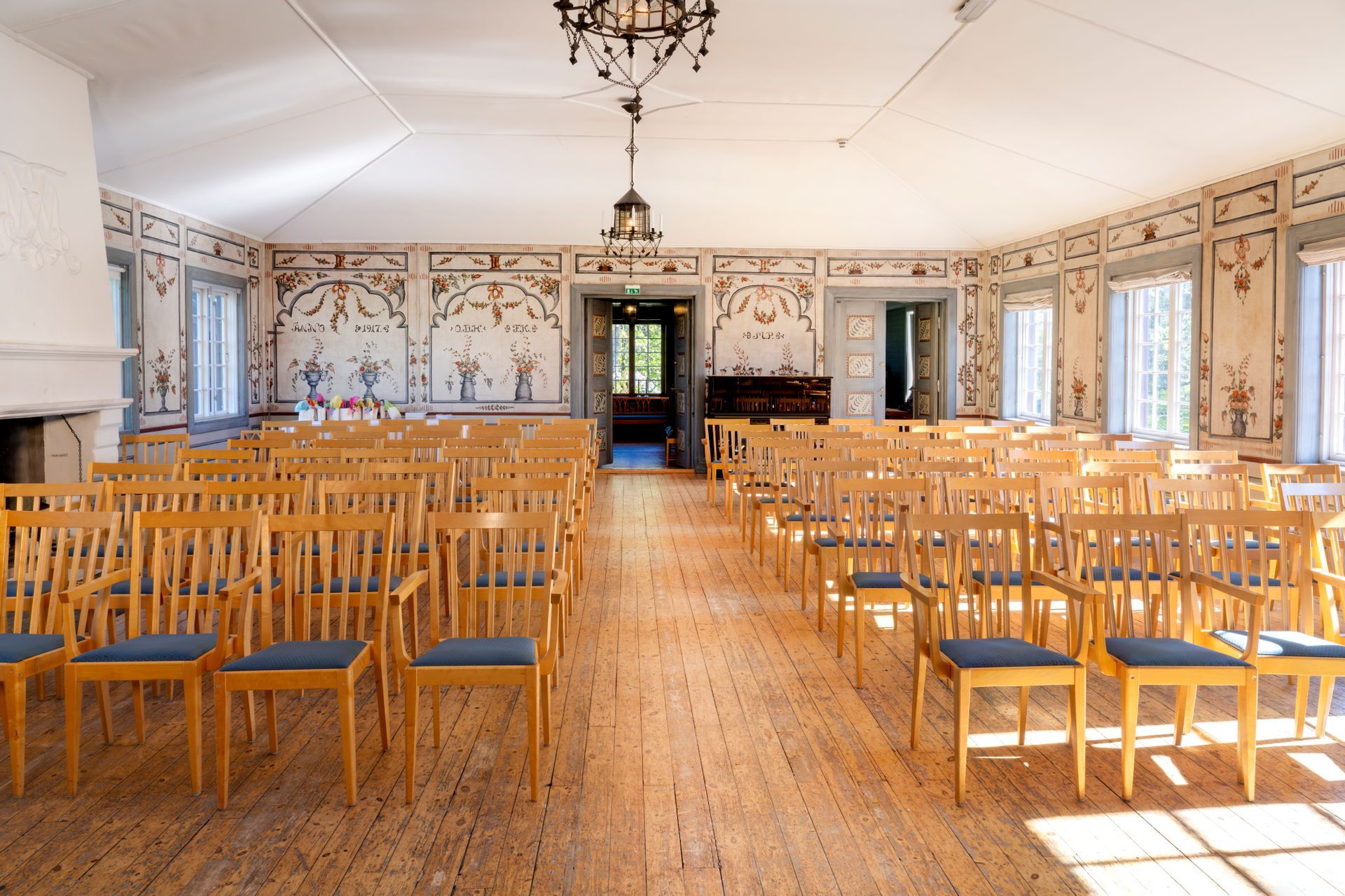 Formelt spisebord plassert nær et vindu med blomstertapet. Fargerike blomster og et tent stearinlys forsterker stemningen.