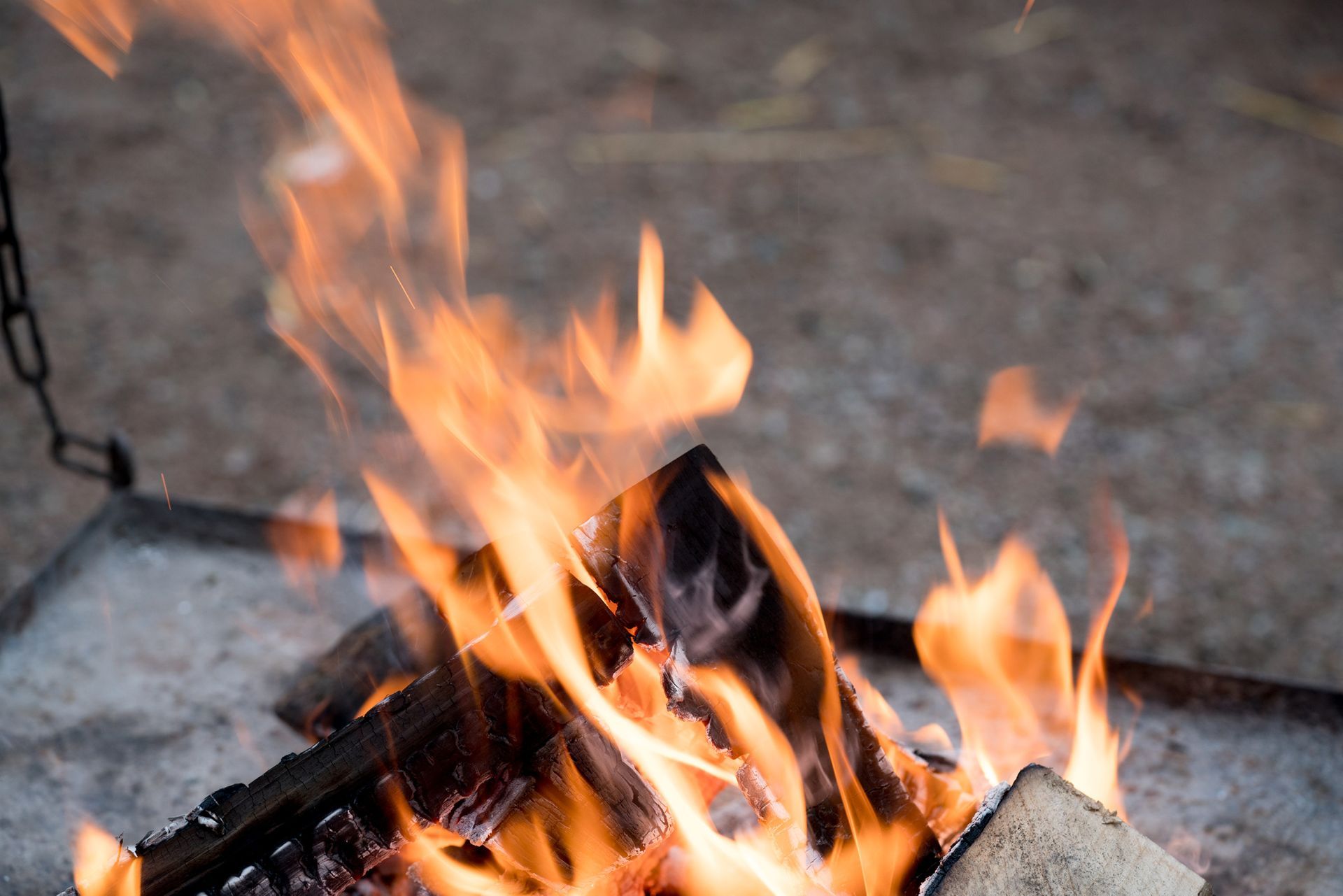 Ild som brenner i en metallbeholder med oransje og gule flammer.
