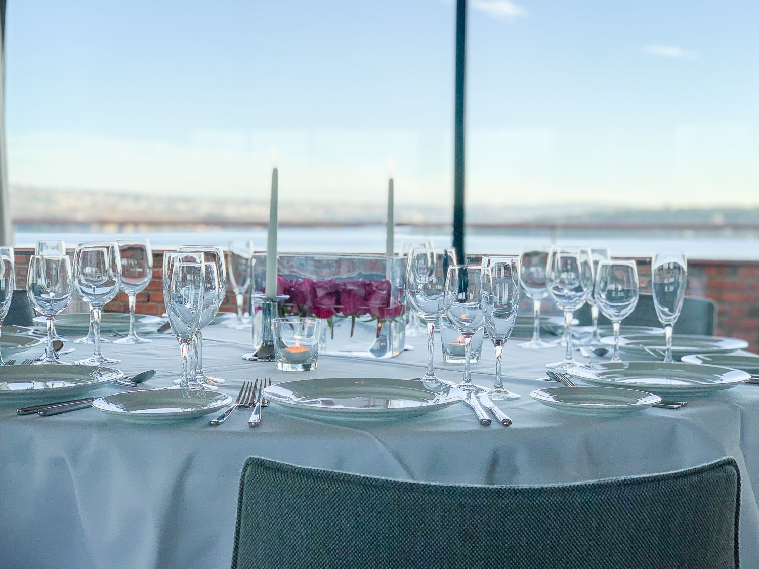 Elegant borddekking for en stor gruppe, med utsikt over vannet i bakgrunnen.
