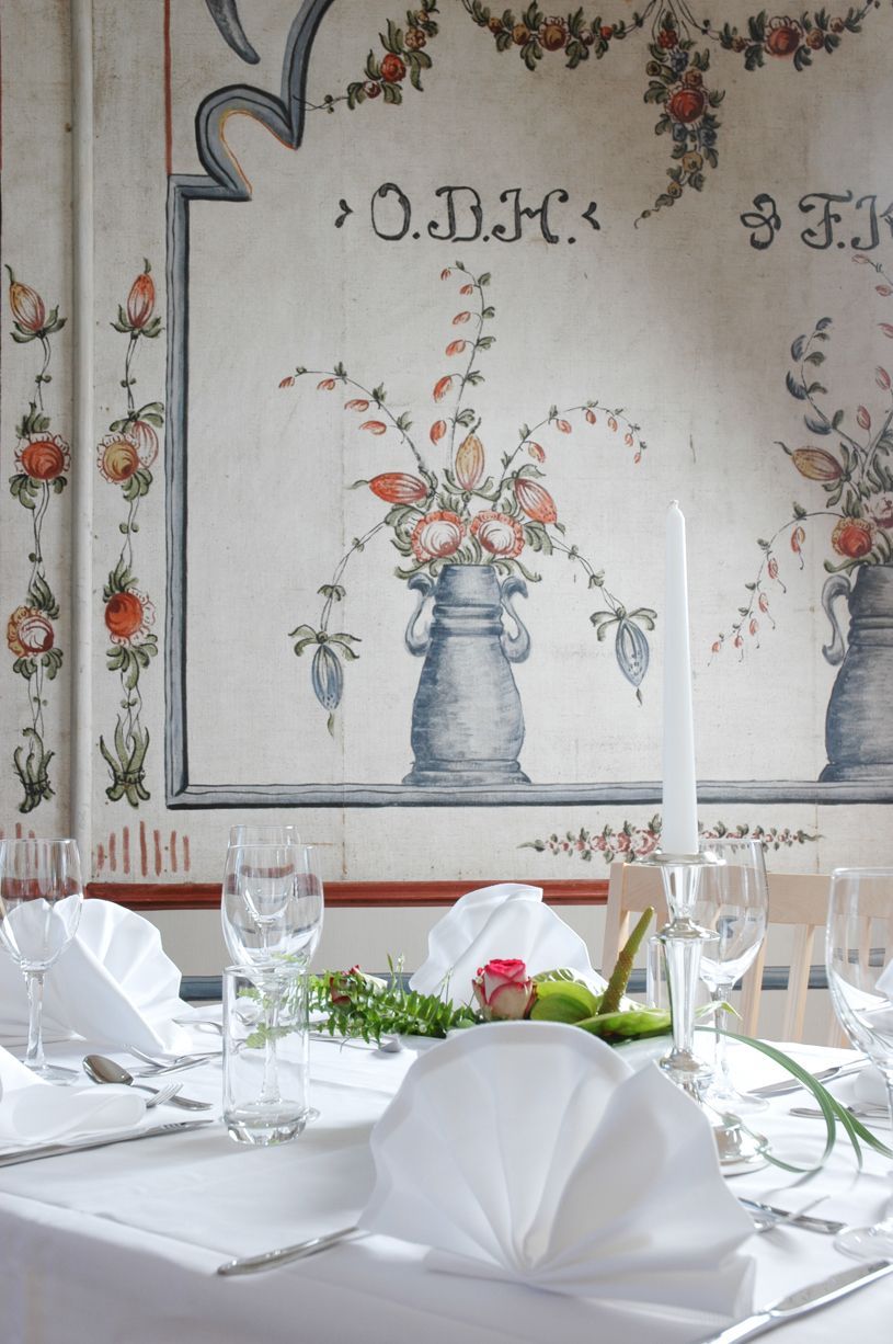 Formell spisestue med dekket bord til måltider, peis og dekorative veggpaneler.