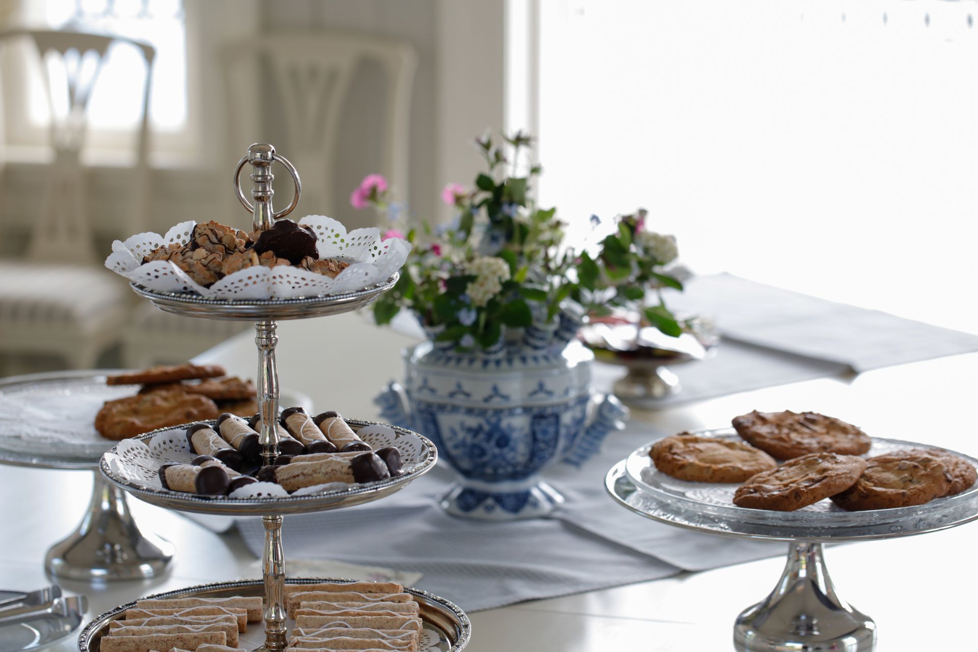 Kjeks på etasjerte brett og et bord med blomster.