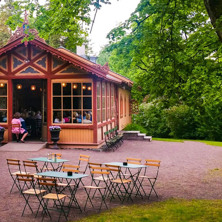 Langt bord dekket til en formell middag i et rustikt rom med peis og vinduer.