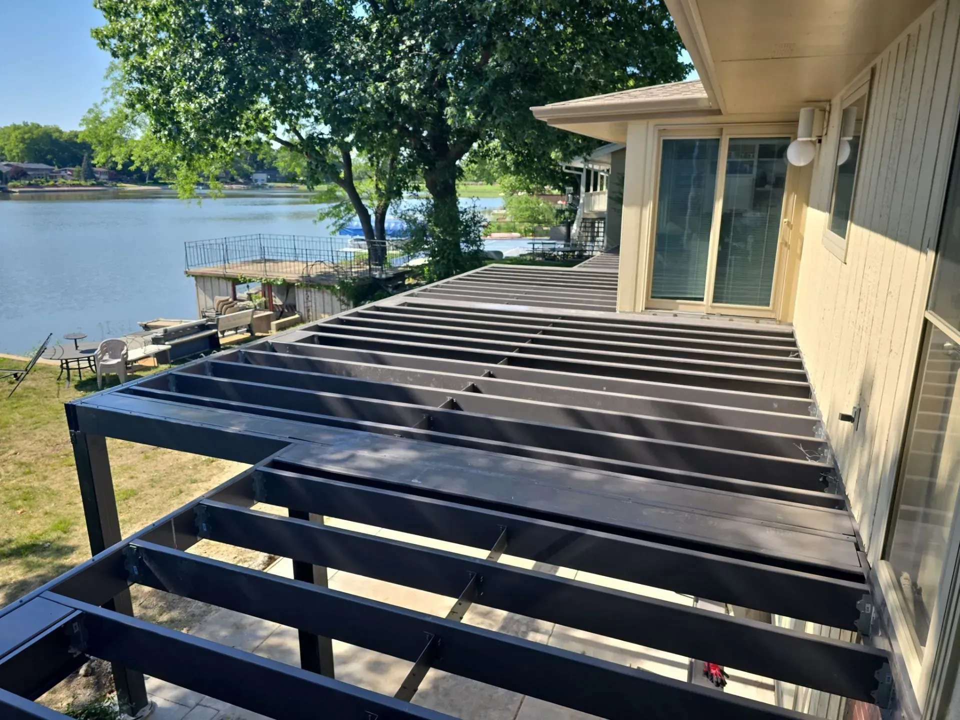A wooden deck with a view of a lake and a house in the background.