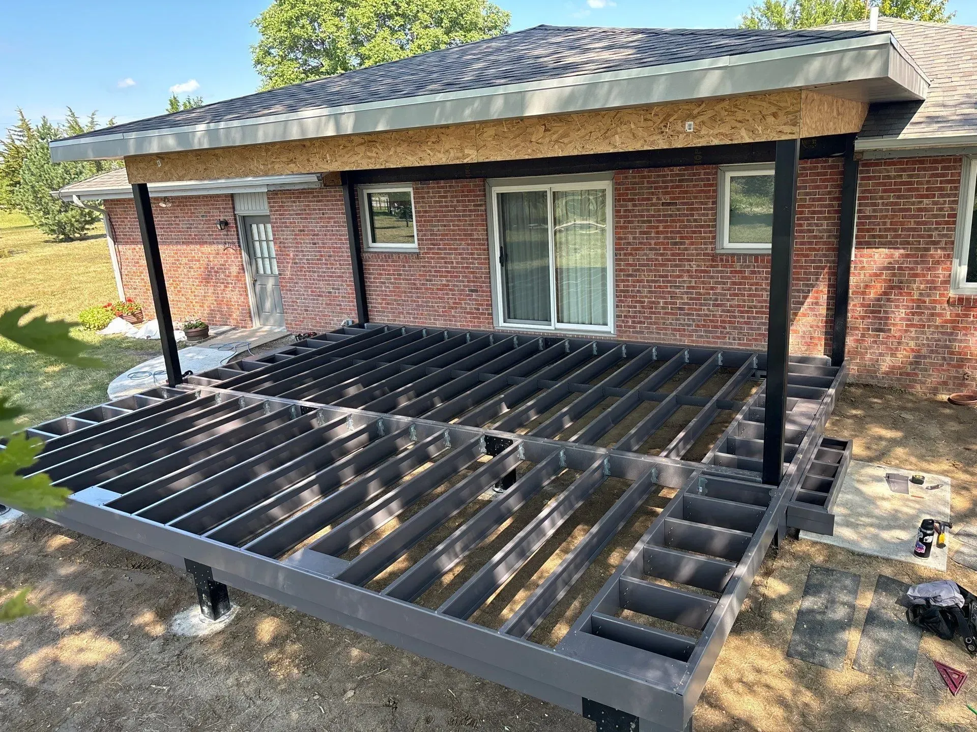 A wooden deck is being built in front of a brick house.