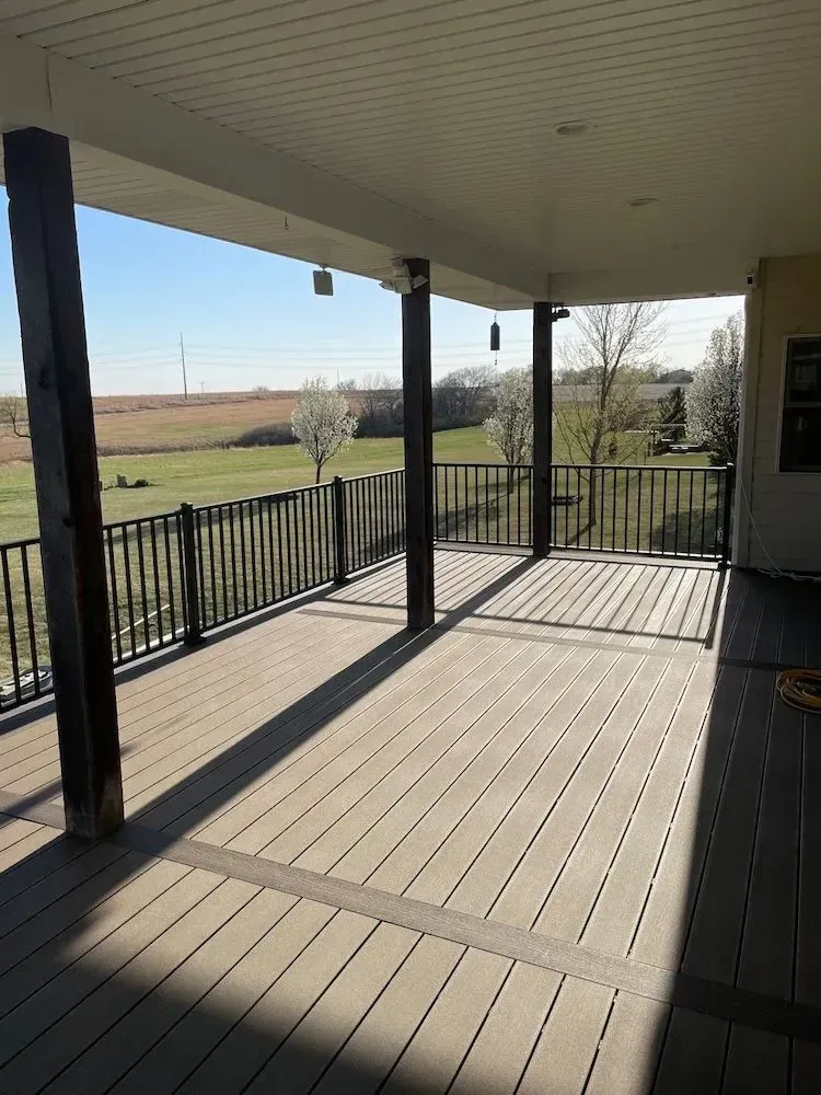 A large deck with a railing and a view of a field.
