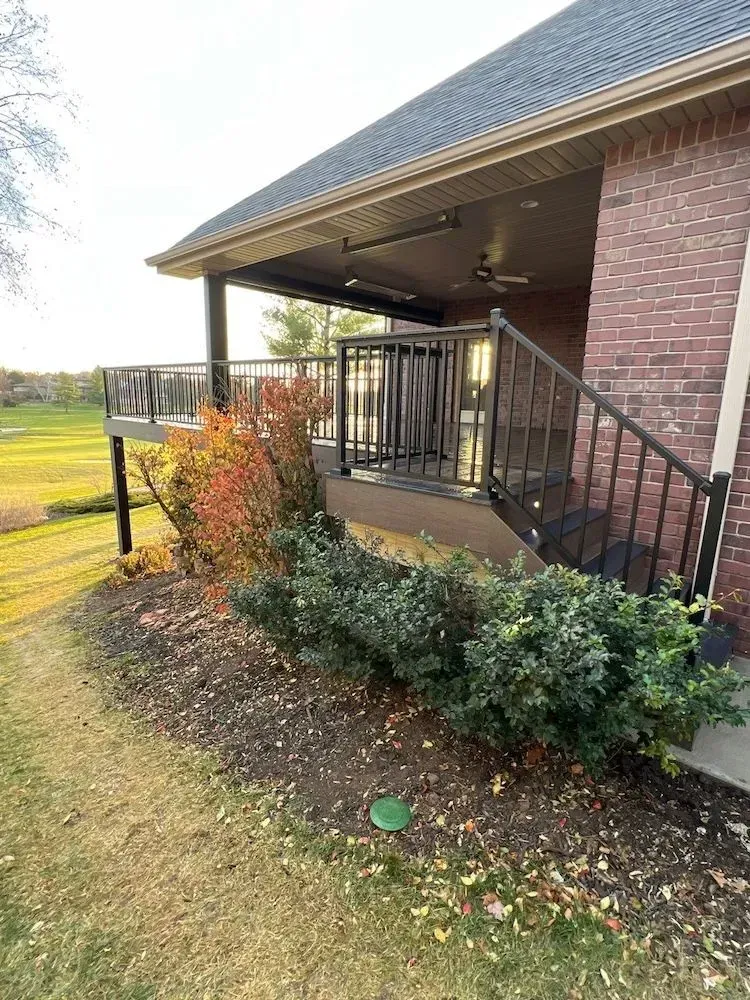 A brick house with a deck and stairs leading up to it.