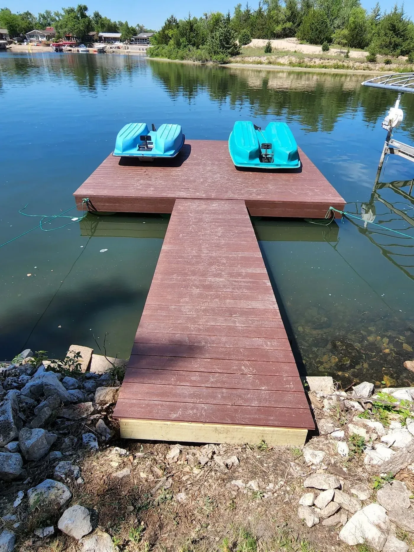 Two pedal boats are sitting on a wooden dock in the middle of a lake.