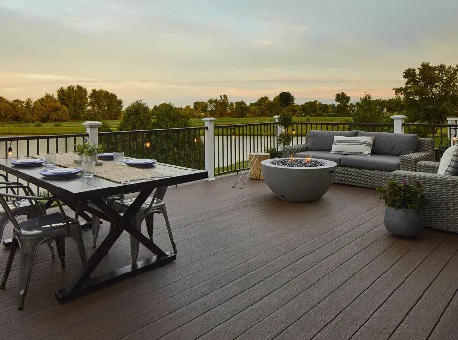 There is a table and chairs on the deck with a fire pit.