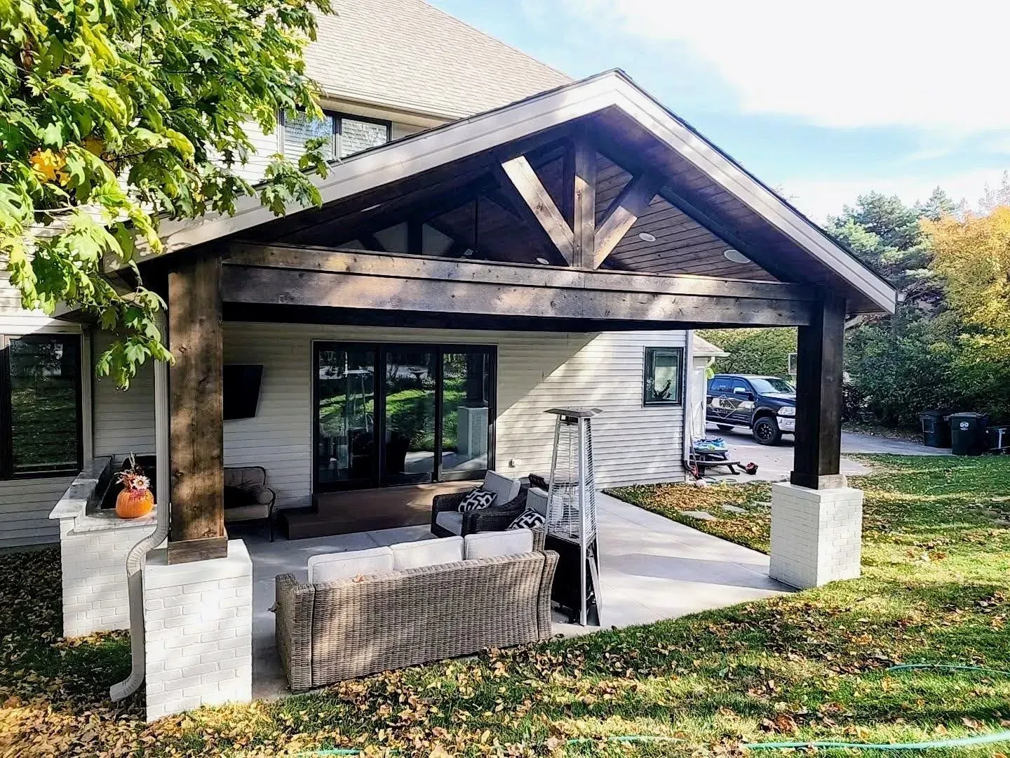 The back of a house with a covered patio with furniture and a fire pit.