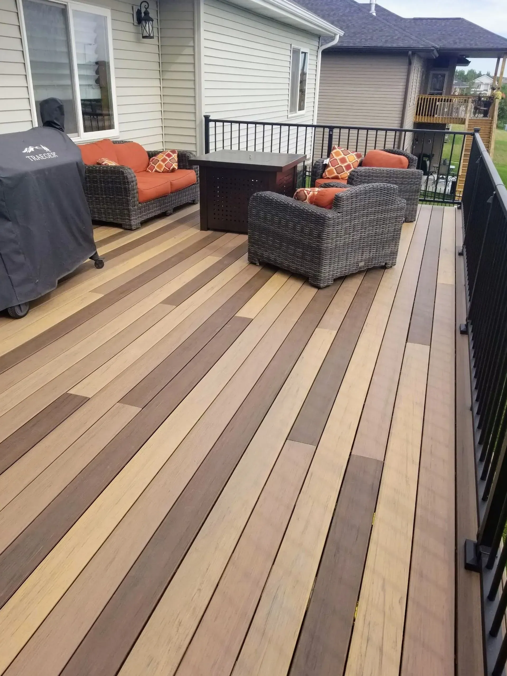 A wooden deck with furniture and a grill on it.