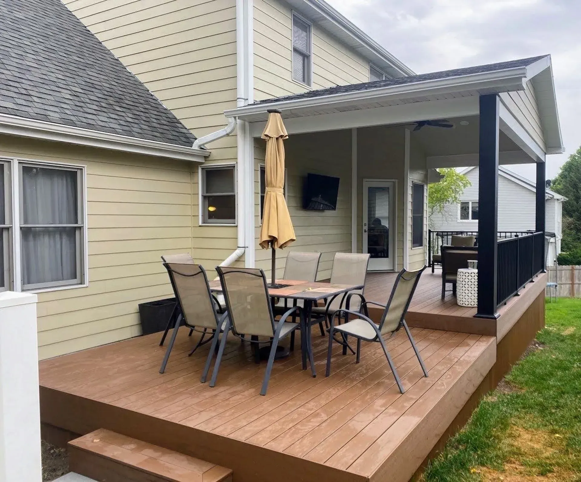 A wooden deck with a table and chairs on it in front of a house.