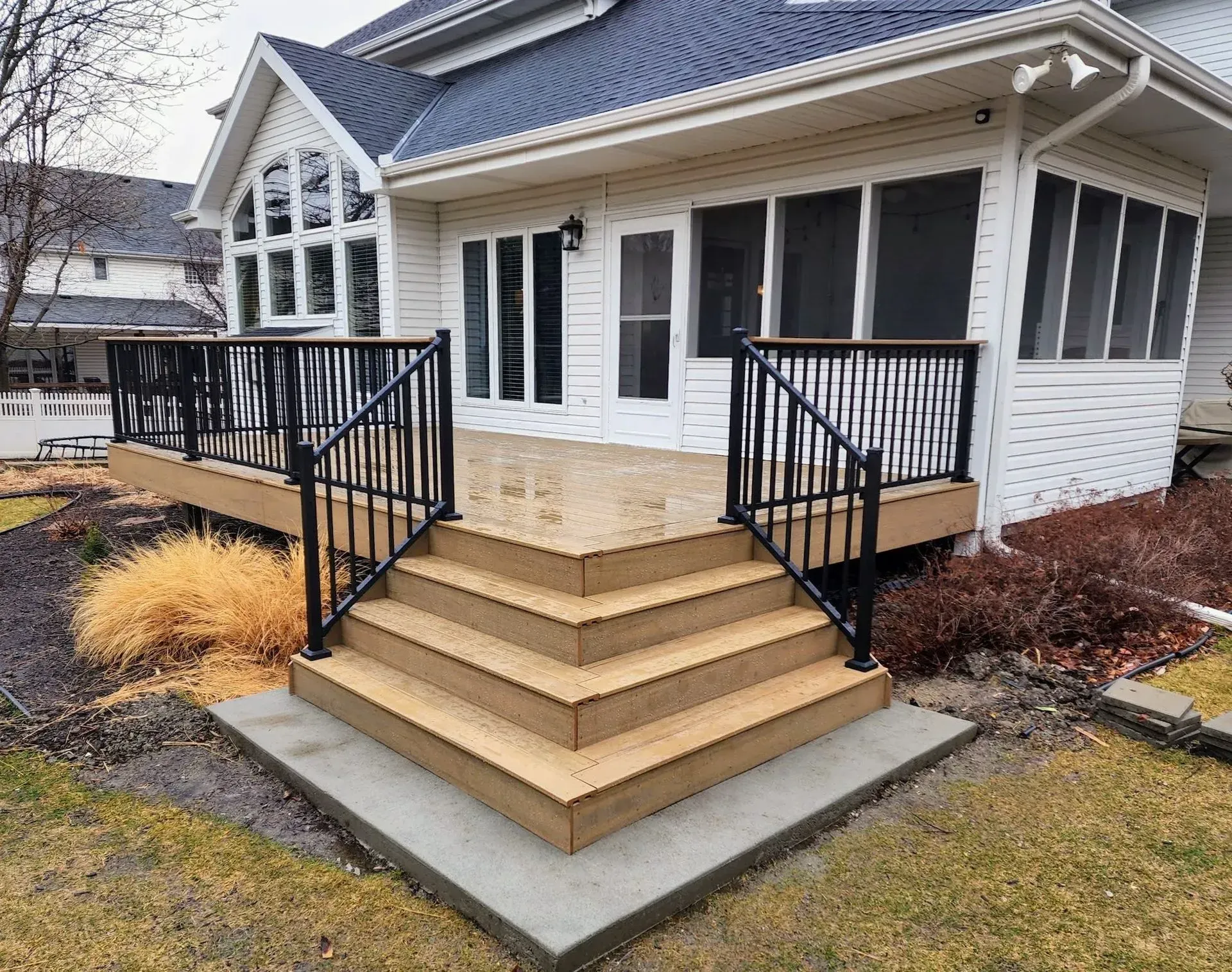 A white house with a screened in porch and a wooden deck.