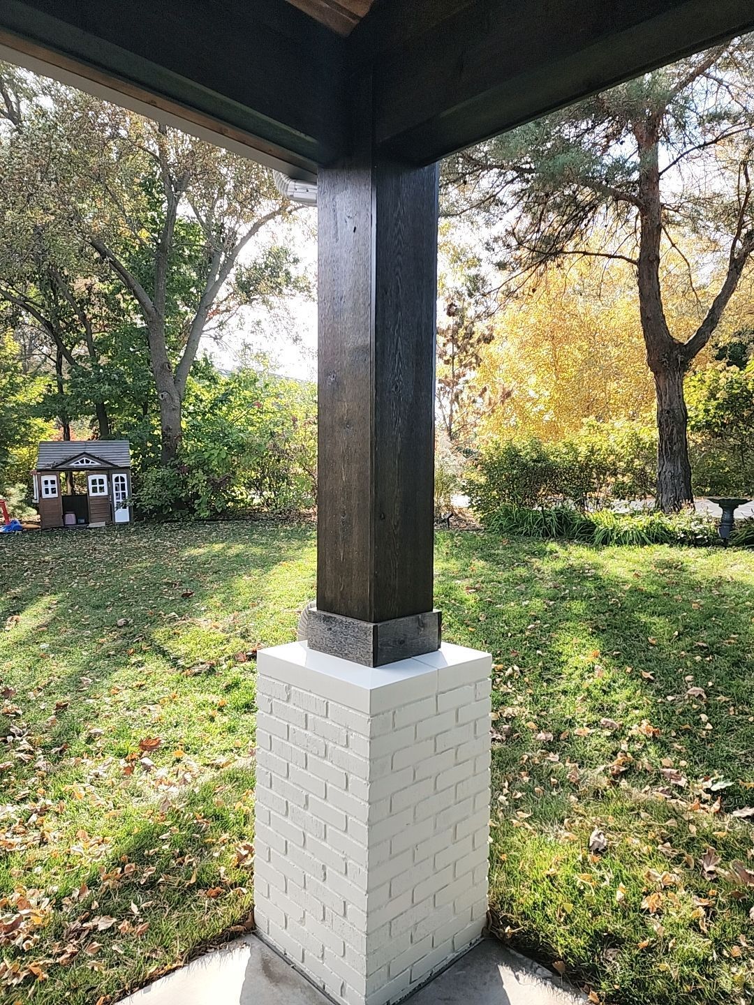 A porch with a wooden post and a white brick column.