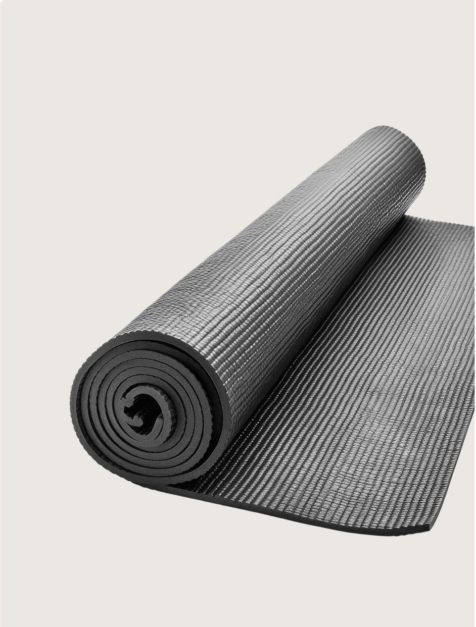 A black, textured exercise or yoga mat partially rolled up against a plain light background.