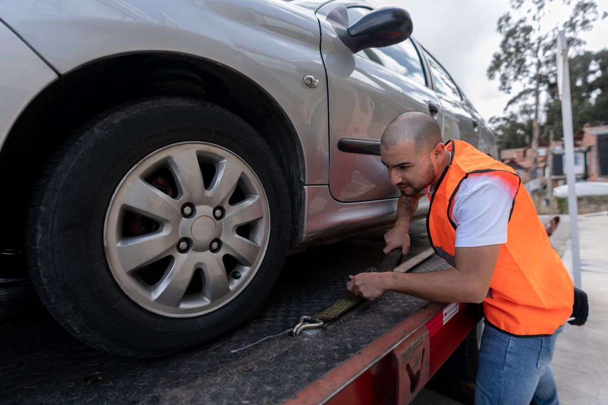A man is towing a car on a tow truck.