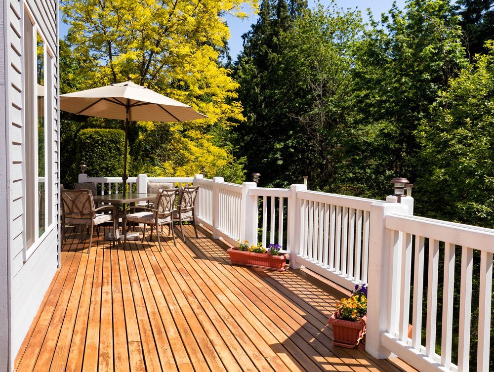 A wooden deck with a white railing and umbrella