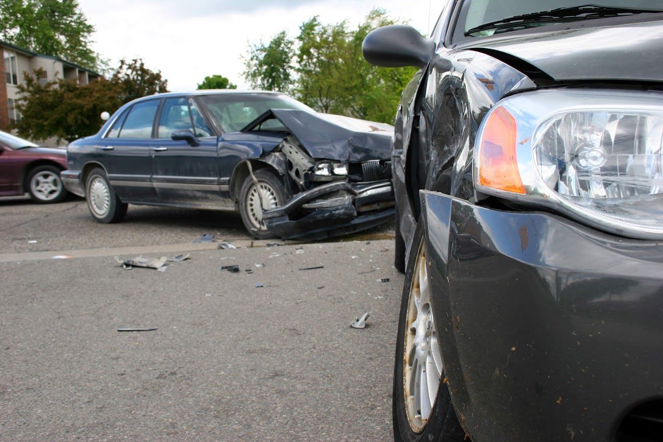 Due auto coinvolte in una collisione, con un'auto nera in primo piano e una berlina danneggiata sullo sfondo.